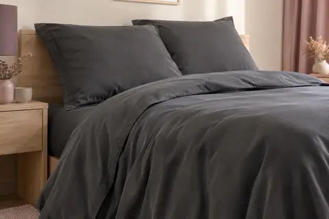 Parure de lit gris foncé en microfibre brossée, avec housse de couette et deux taies assorties sur un lit