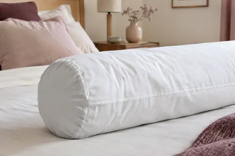 Protège-traversin blanc en coton molletonné posé sur un traversin, avec le tissu et ses plis visibles en gros plan.