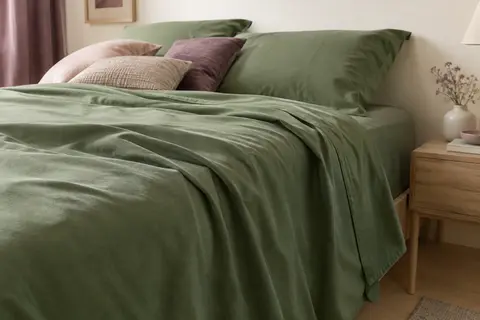 Drap plat en coton vert uni posé sur un lit, avec ses plis et son tombé naturel visibles