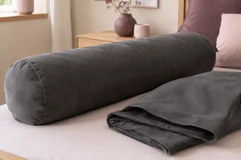 Deux taies de traversin en microfibre gris foncé, dont une installée sur un traversin dans une chambre claire.