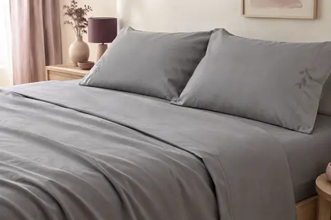 Parure de lit grise en microfibre avec drap-housse profond et deux taies brodées sur un lit