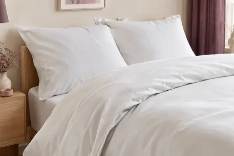 Parure blanche en microfibre brossée posée sur un lit dans une chambre aux tons doux