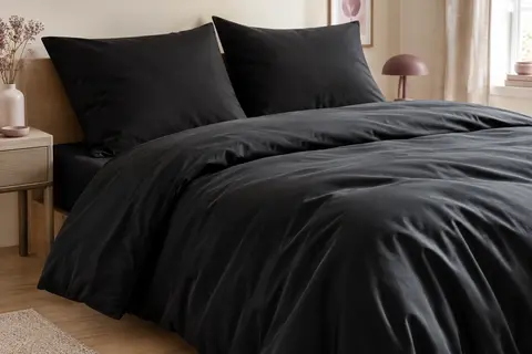 Parure de lit noire en microfibre avec housse de couette et deux taies assorties sur un lit soigneusement préparé.