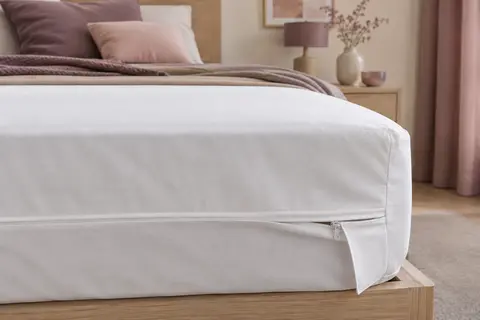 Housse intégrale blanche en polyester installée sur un matelas, avec un détail de la fermeture à glissière.